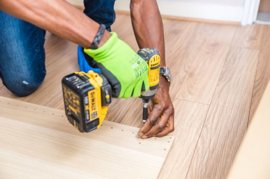 Worker drilling into a wooden floor with a cordless drill