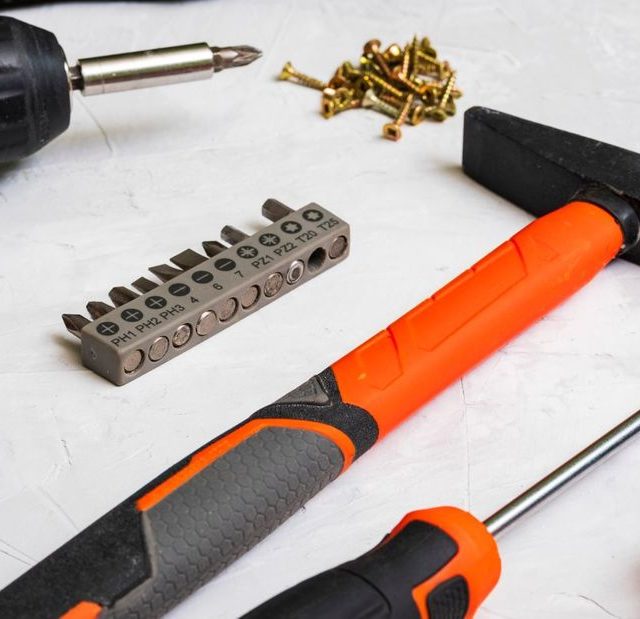 Drill bits, screws and a hammer on a white surface